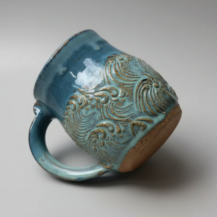 Turquoise handmade pottery mug with wave design perfect for coffee or tea lovers