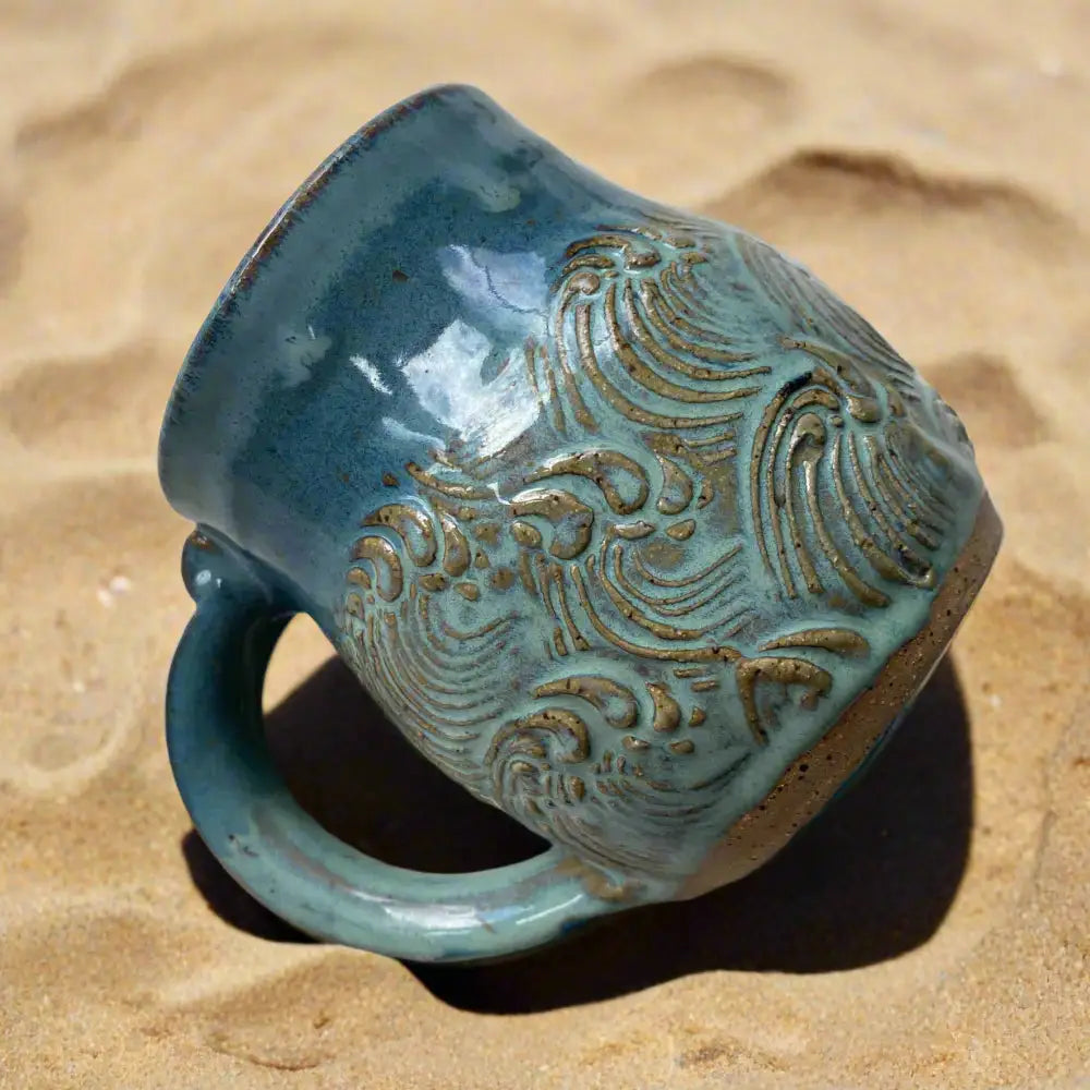 Teal handmade pottery mug with wave design and embossed pattern, perfect for coffee