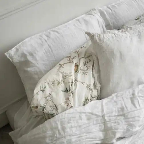 White bedding with floral pillow.