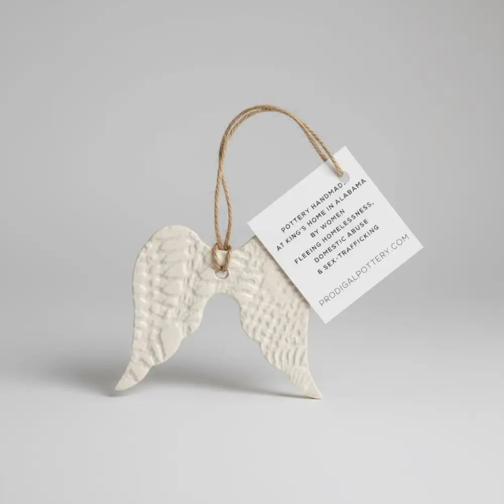 White ceramic angel wing ornament with textured surface and twine loop