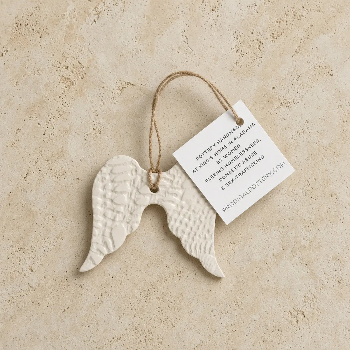 White ceramic angel wing ornament with textured surface and natural twine loop for year-round gifting