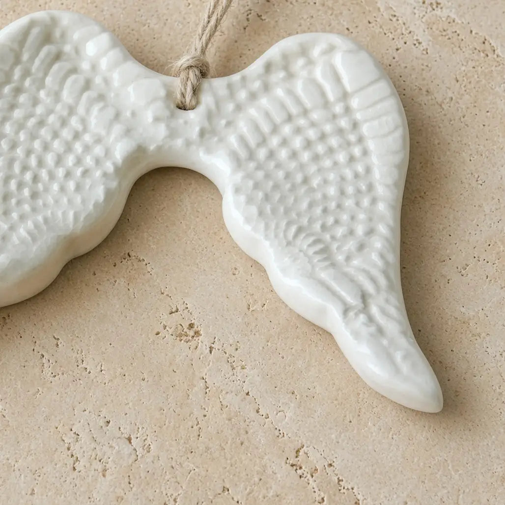 White ceramic angel wing ornament with textured feathers and natural twine loop for year-round gifting decor