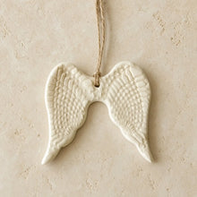White ceramic angel wing ornament with textured feather patterns and natural twine hanger for year-round gifting