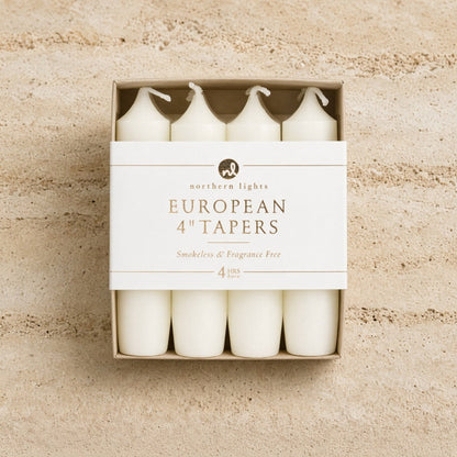 Set of four white unscented taper candles for standard taper holders in a minimalist box measuring 4 inch