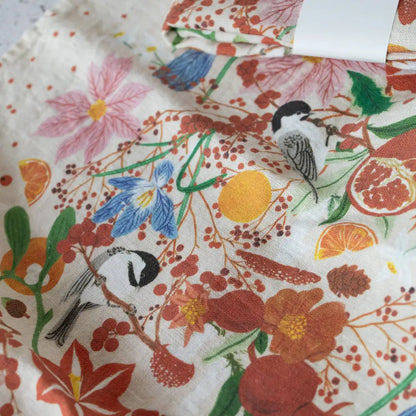 Vibrant floral bird print linen tea towel in oranges, reds, greens on white
