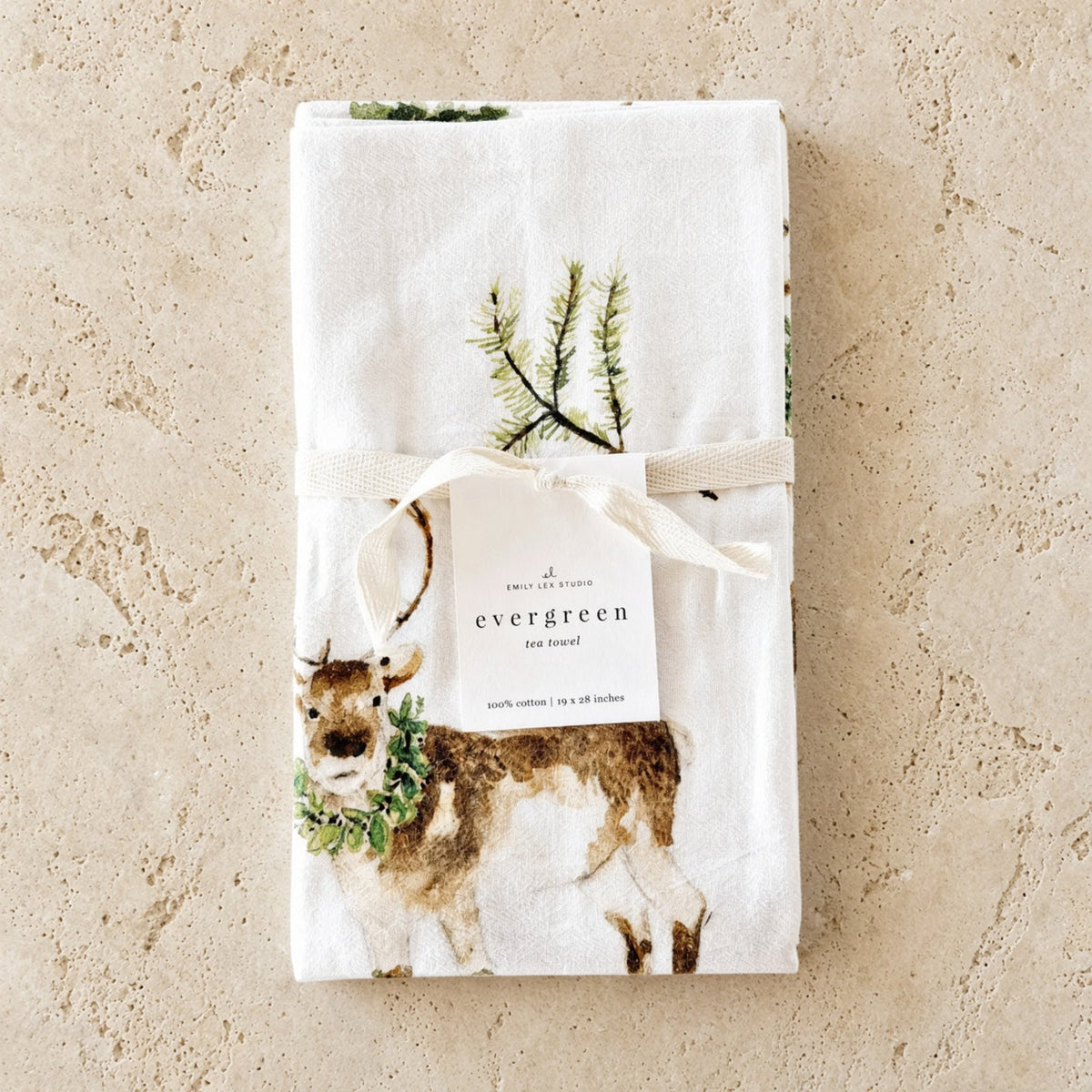 White cotton tea towel with a watercolor deer and greenery tied with a ribbon paired with african zulu trivet