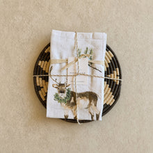 White linen tea towel with brown deer and greenery tied with twine paired with african zulu trivet nest