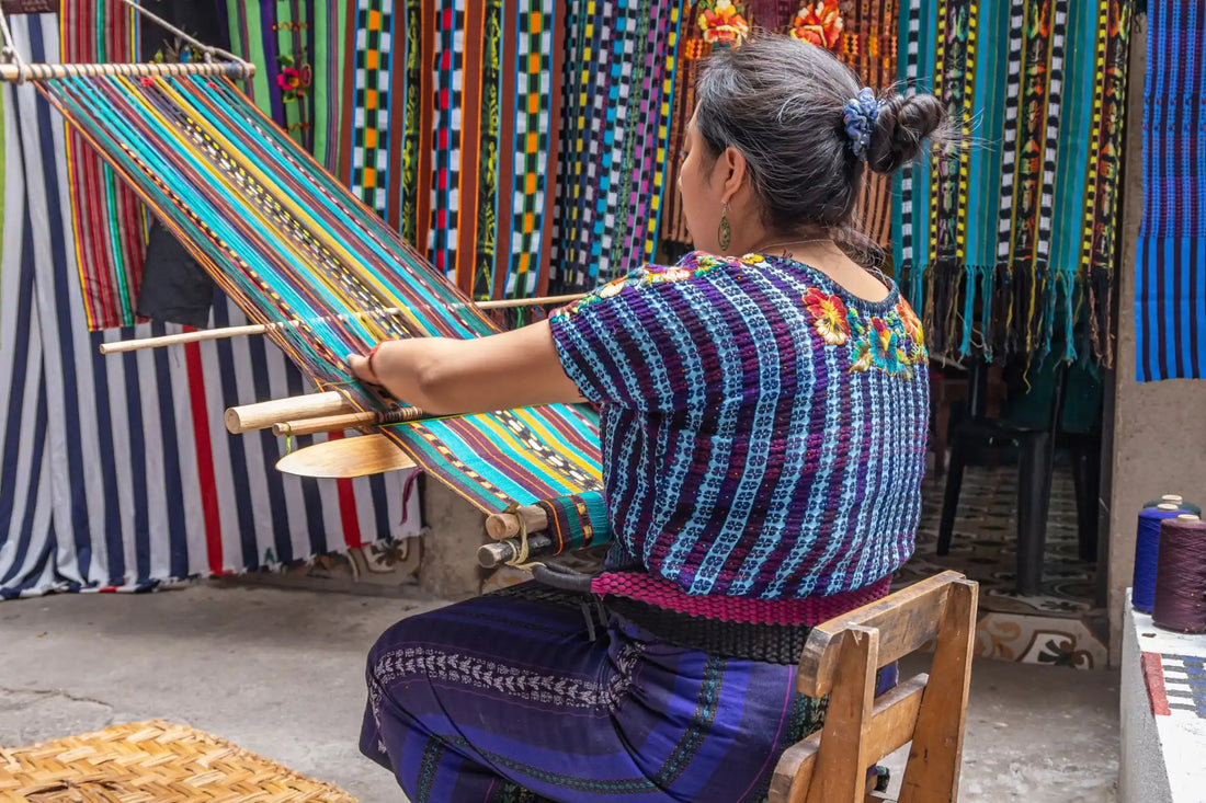 Woman weaving a colorful textile on a backstrap loom.