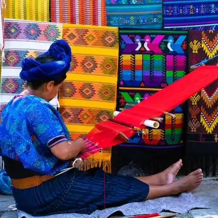 A woman weaving a vibrant red textile.