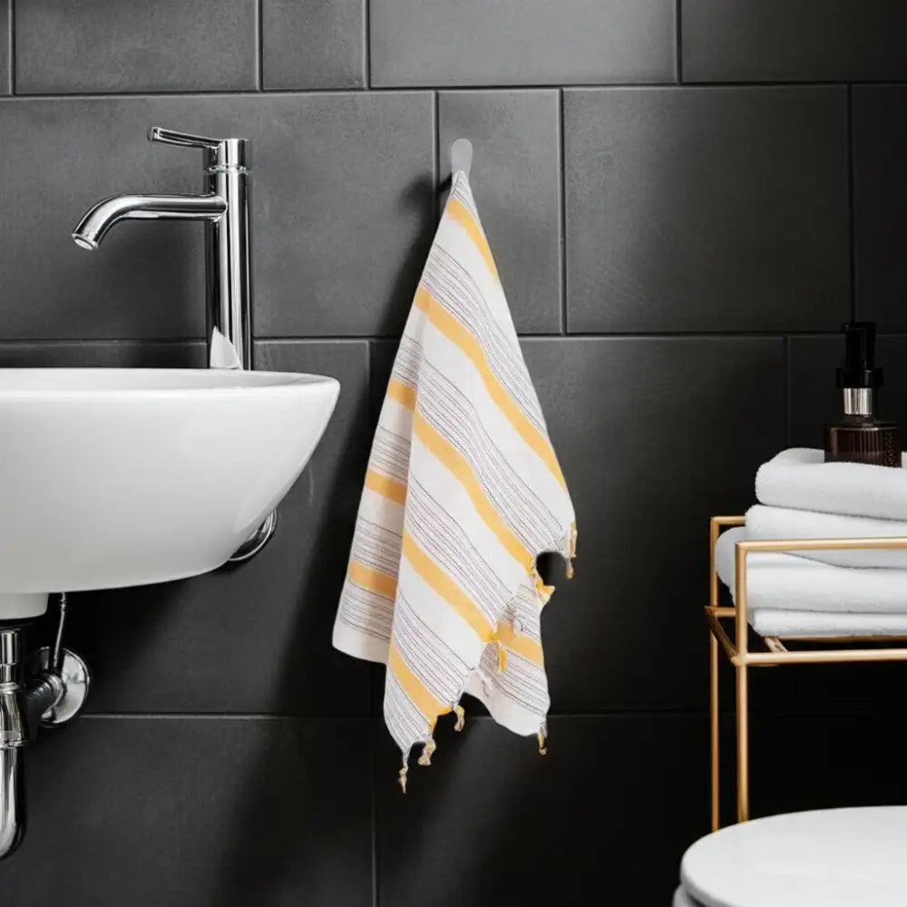 Ivory and yellow Turkish cotton hand towel with tassels hanging on a hook